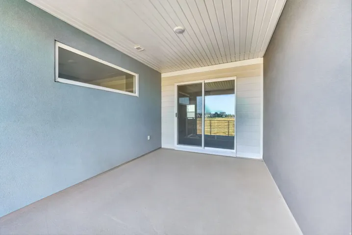 Covered outdoor patio with a concrete floor, horizontal window, and sliding glass door