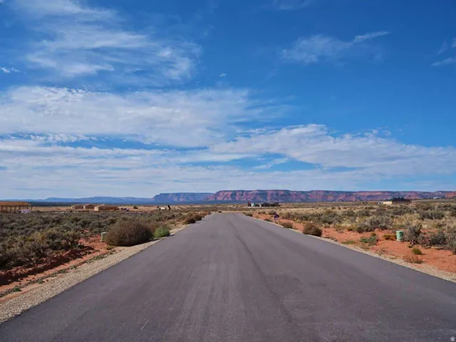 Paved road surface with desert landscaping and distant mesa formations