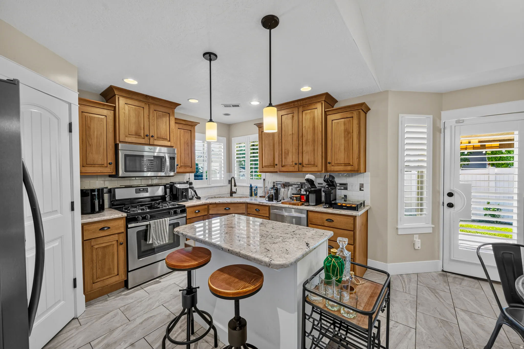 Full kitchen with wood cabinetry, stainless steel appliances, a corner sink, and an island with seating