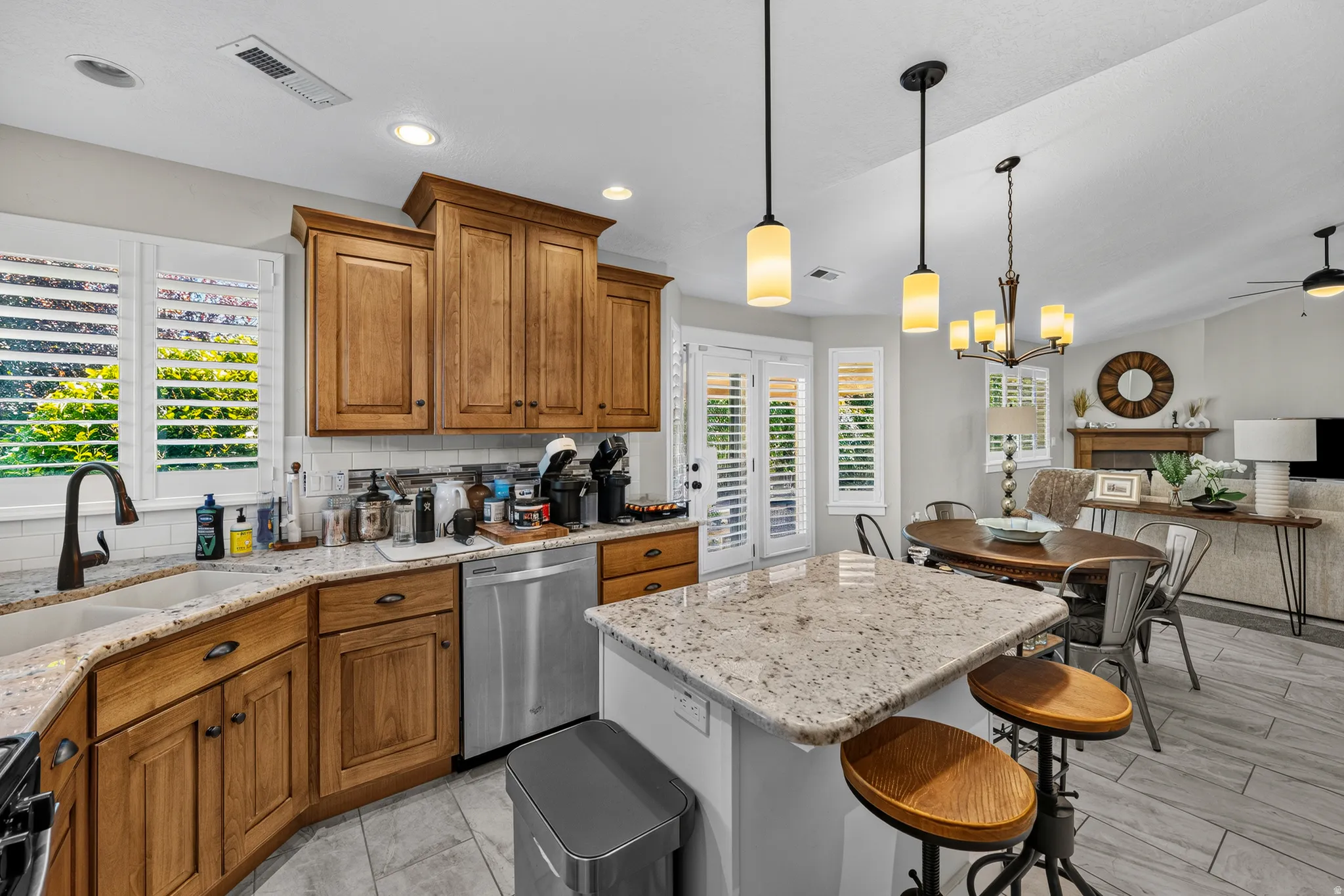 Kitchen featuring wood cabinetry, light-toned granite countertops, a double-basin sink with a gooseneck faucet, and white subway tile backsplash