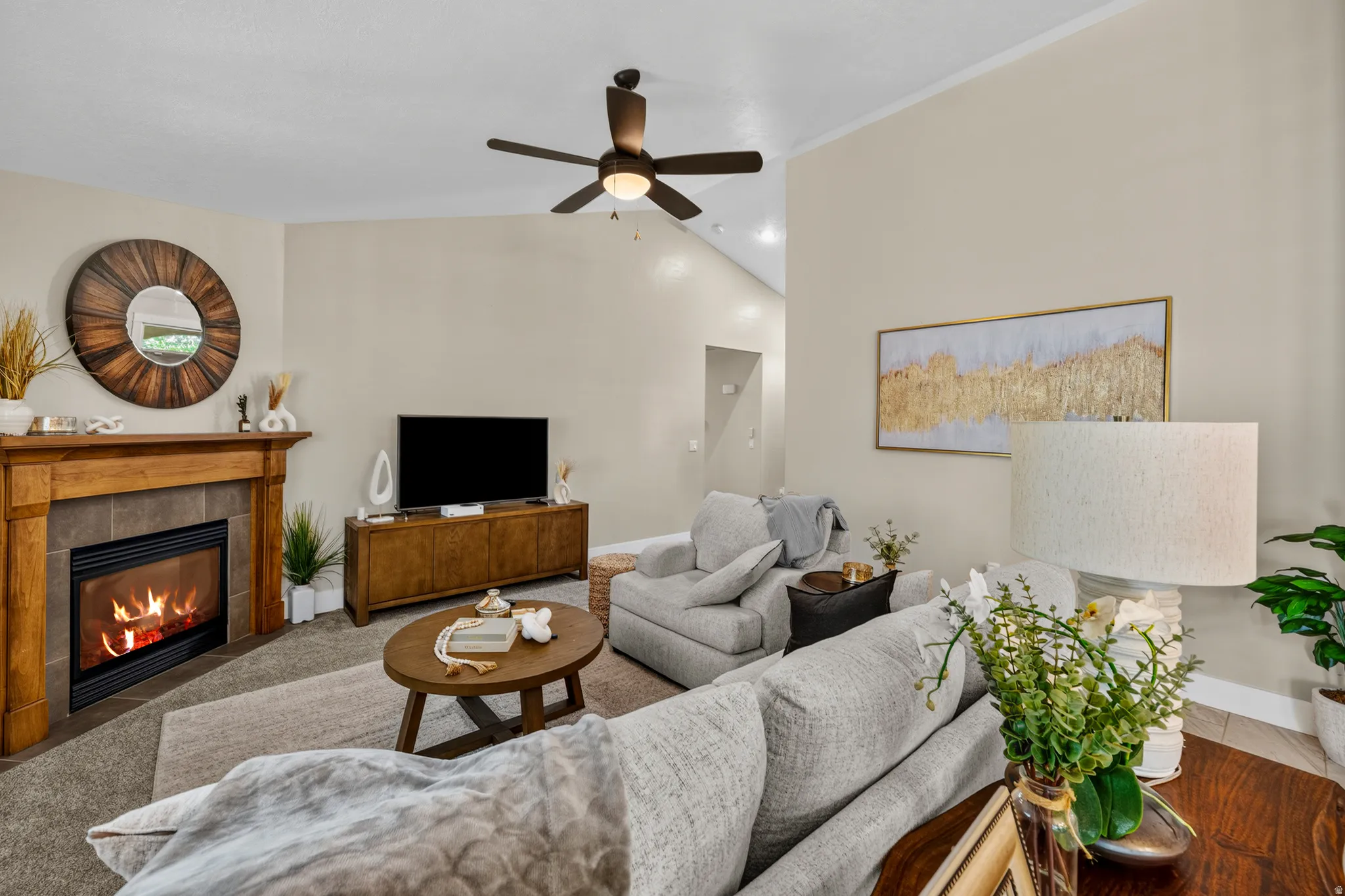 Living space featuring a natural wood mantel, a built-in fireplace with a tile surround, and a ceiling fan with integrated lighting