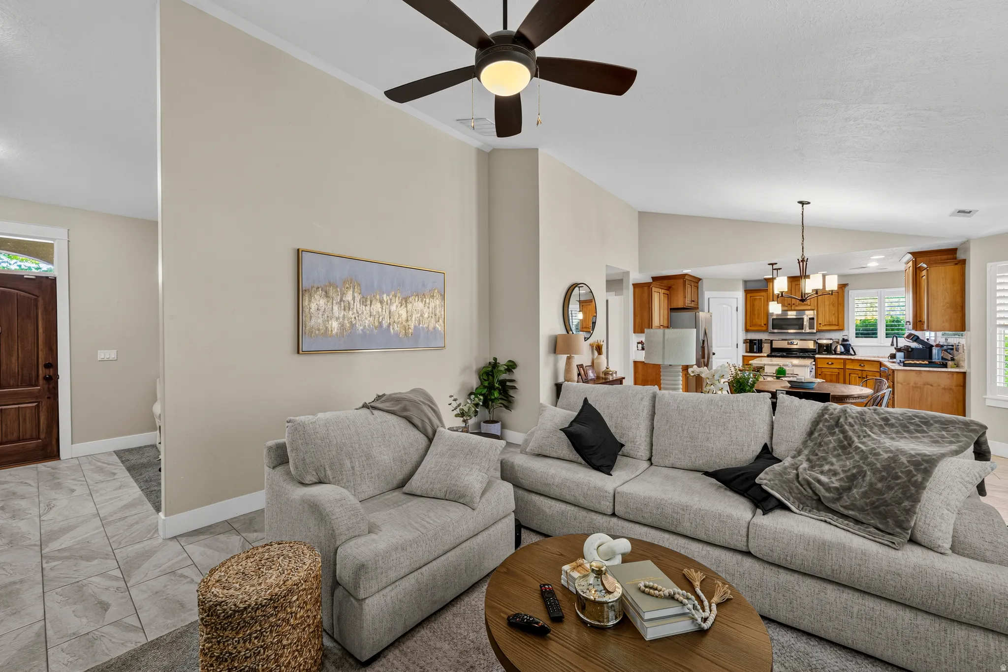 Vaulted ceiling with a ceiling fan, tiled entry flooring, wood-finish front door, recessed lighting, and kitchen with wood cabinetry
