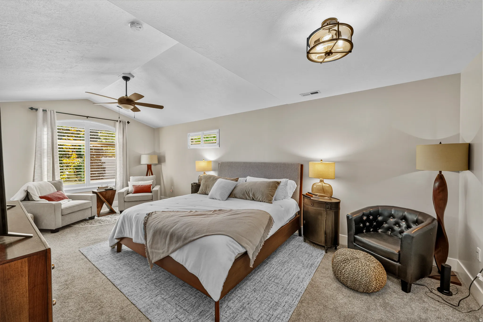 Vaulted ceiling with a ceiling fan, dual windows, and wall-to-wall carpeting