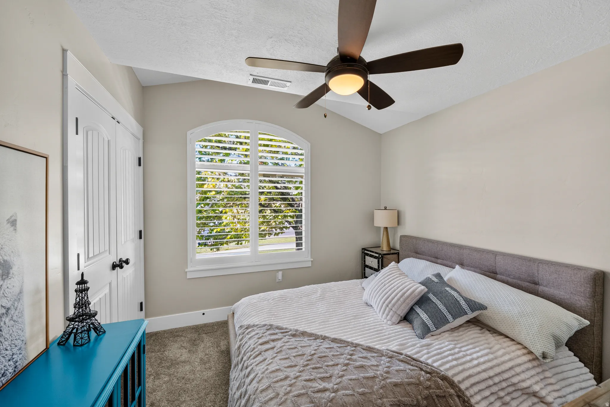 Vaulted ceiling with a ceiling fan, arched window with plantation shutters, and a paneled bifold closet door