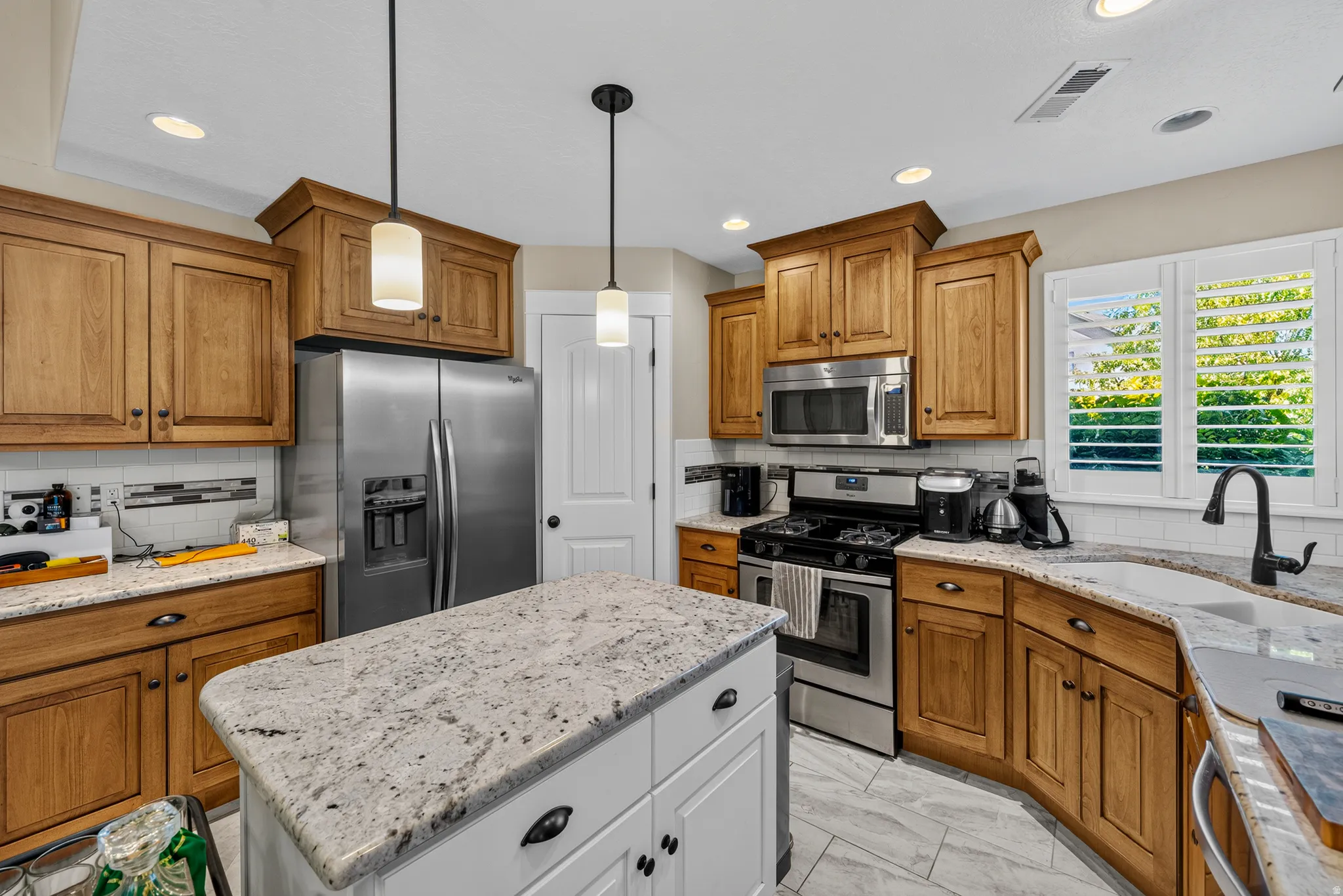 Stainless steel appliances, recessed lighting, tile flooring, stone countertops, and wood cabinetry
