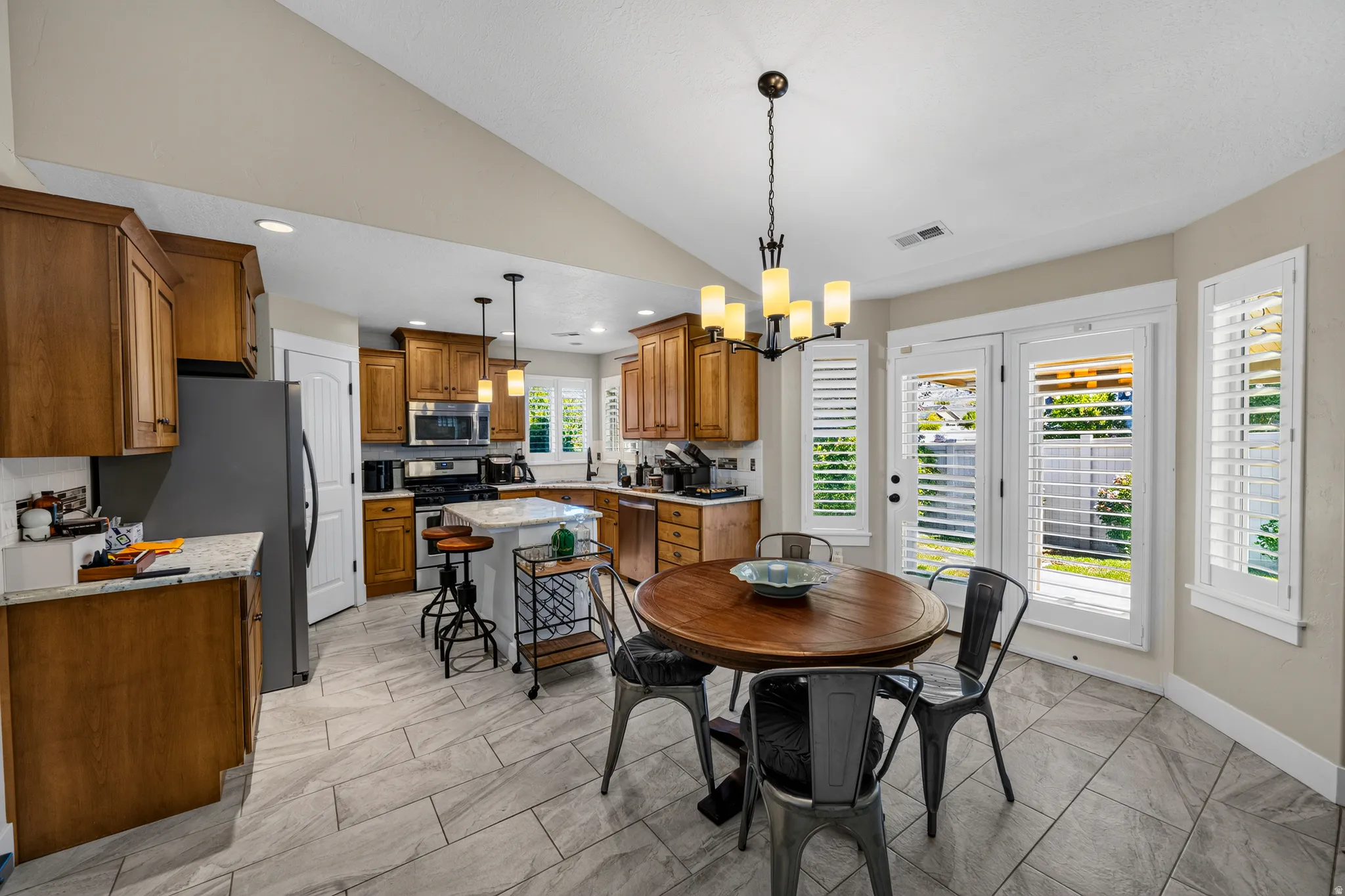 Kitchen featuring wood cabinetry, stainless steel appliances, a center island with countertop seating, and tile flooring
