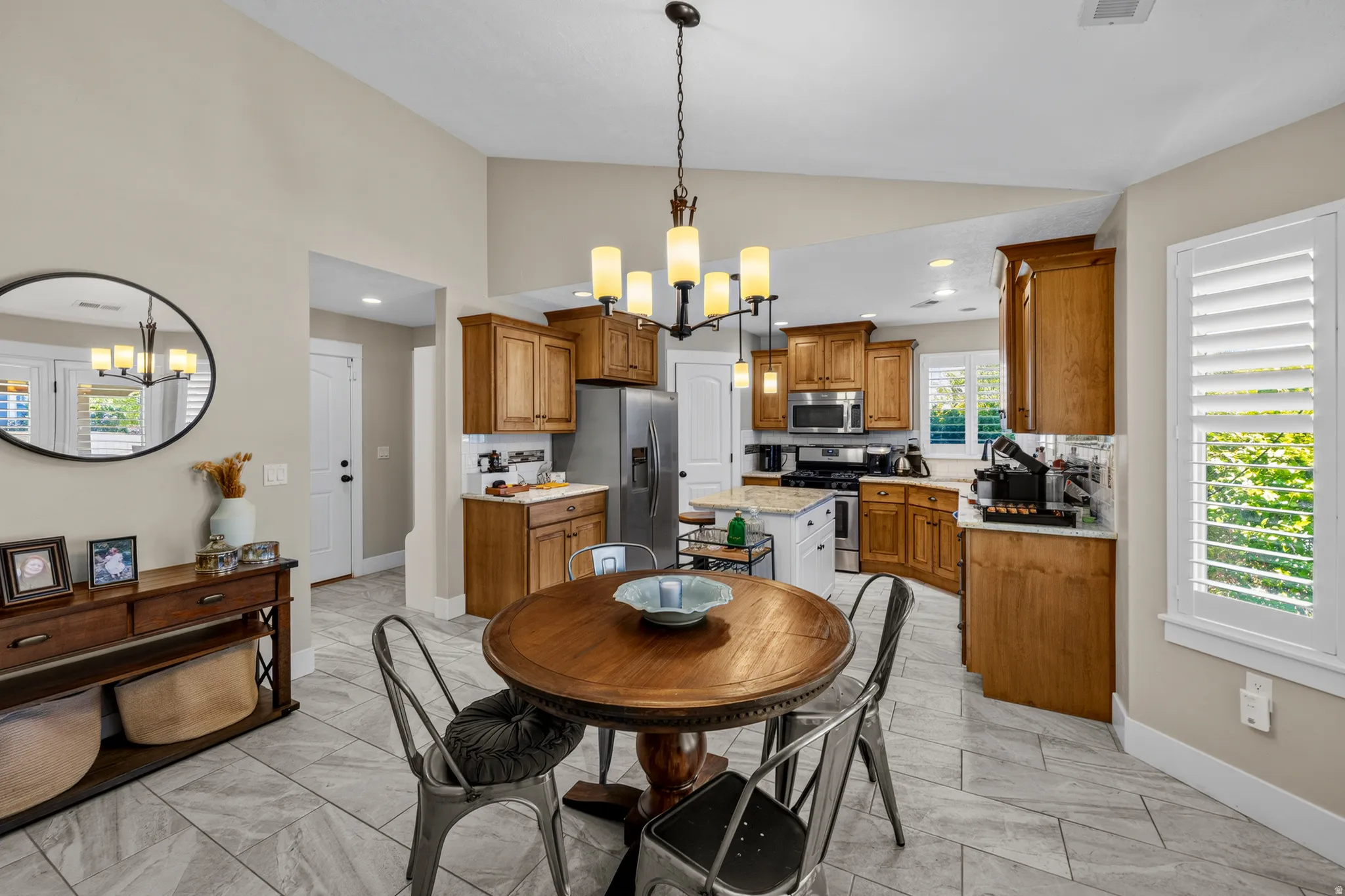 Vaulted ceiling, tile flooring, wood cabinetry, stainless steel appliances, and white plantation shutters