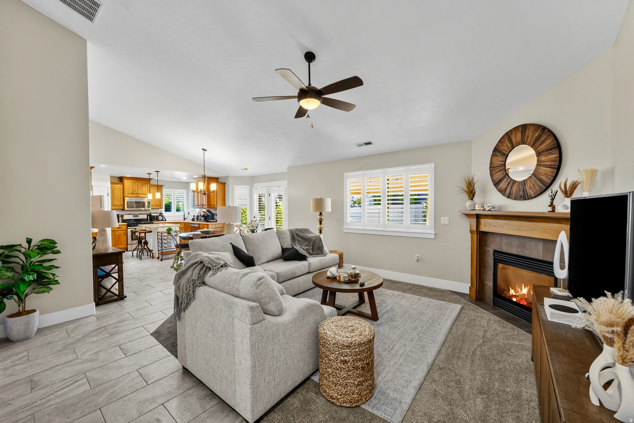 Vaulted ceilings, wood-finish flooring, ceiling fan, fireplace with wood mantel, and interior window shutters