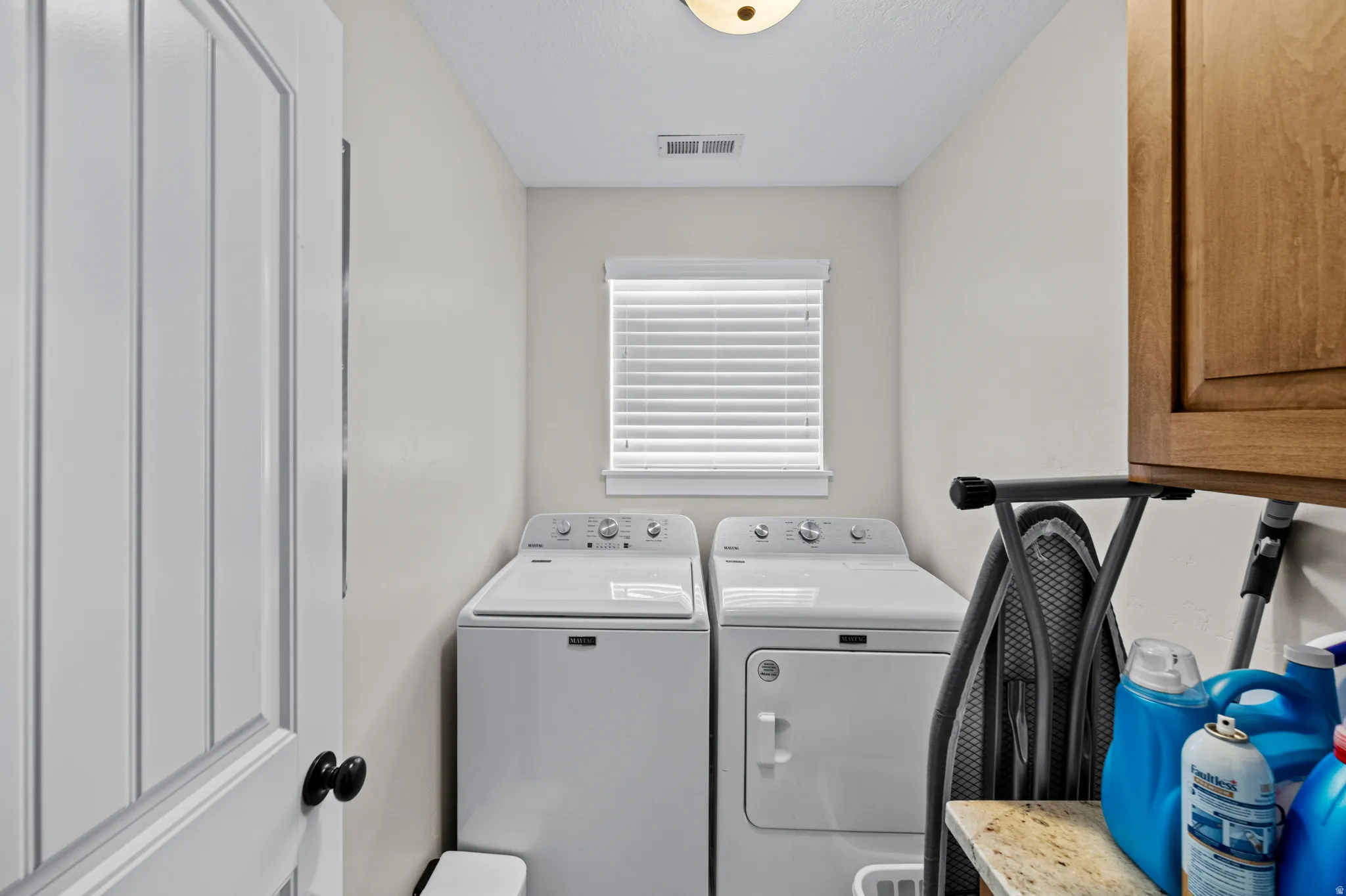 Dedicated laundry space featuring a window, built-in cabinetry, and a countertop