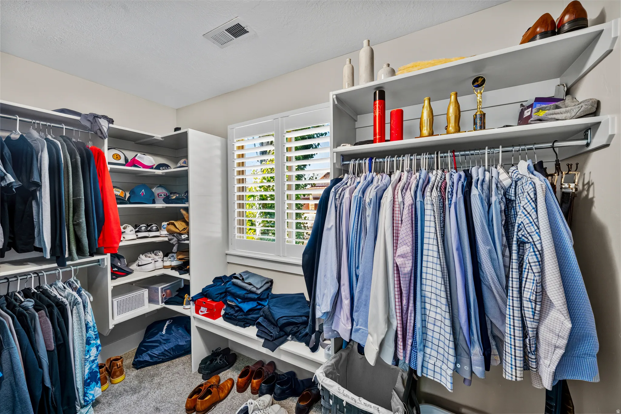 Custom closet system with white shelving, multiple hanging rods, and built-in storage