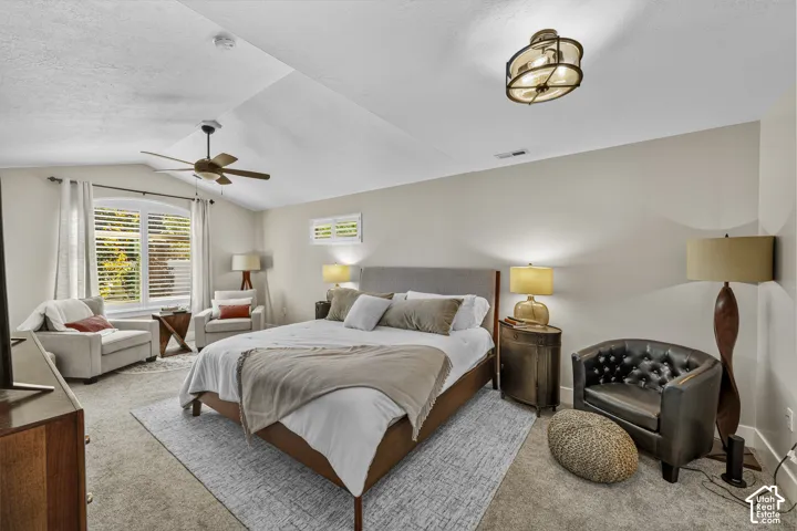 Vaulted ceiling with a ceiling fan, dual windows, and wall-to-wall carpeting