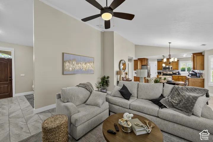 Vaulted ceiling with a ceiling fan, tiled entry flooring, wood-finish front door, recessed lighting, and kitchen with wood cabinetry