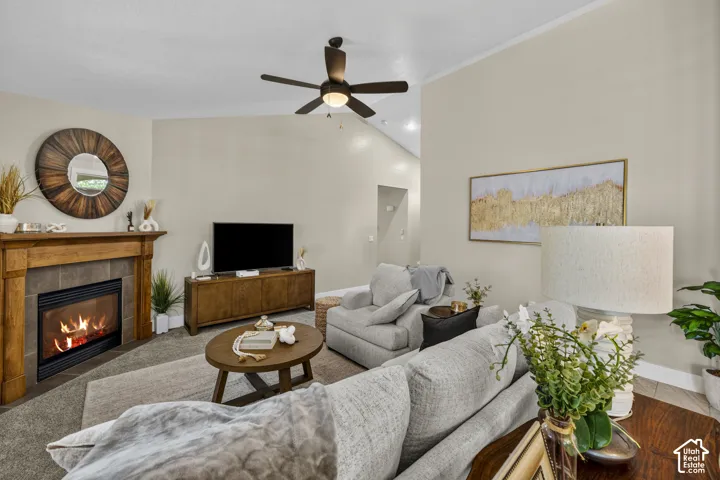 Living space featuring a natural wood mantel, a built-in fireplace with a tile surround, and a ceiling fan with integrated lighting