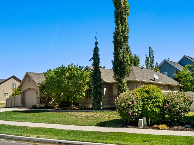 Manicured front yard with mature landscaping, a paved driveway, and an attached garage