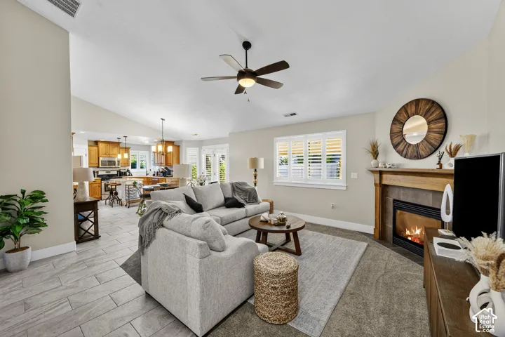 Vaulted ceilings, wood-finish flooring, ceiling fan, fireplace with wood mantel, and interior window shutters