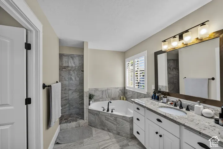 Spacious bathroom with a walk-in shower, soaking tub, and a vanity featuring a granite-style countertop and dual sinks