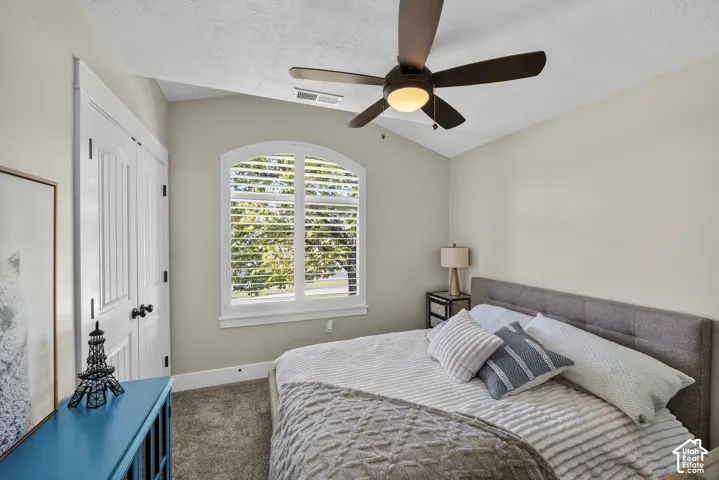 Vaulted ceiling with a ceiling fan, arched window with plantation shutters, and a paneled bifold closet door
