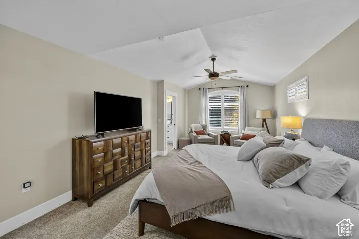 Vaulted ceiling with ceiling fan, large arched window, plantation shutters, and carpeted flooring
