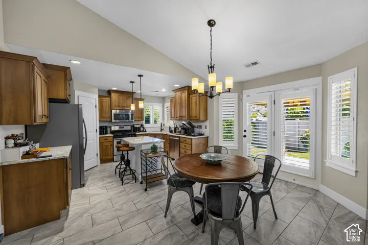 Kitchen featuring wood cabinetry, stainless steel appliances, a center island with countertop seating, and tile flooring
