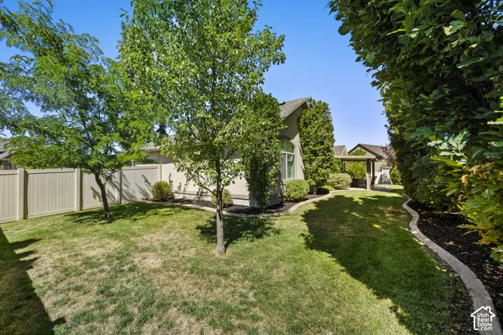 Expansive backyard featuring a manicured lawn, established trees, and perimeter fencing