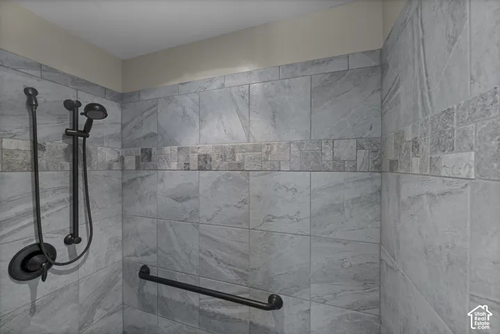 Tiled shower with a decorative mosaic accent band and dark bronze fixtures