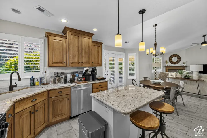 Kitchen featuring wood cabinetry, light-toned granite countertops, a double-basin sink with a gooseneck faucet, and white subway tile backsplash