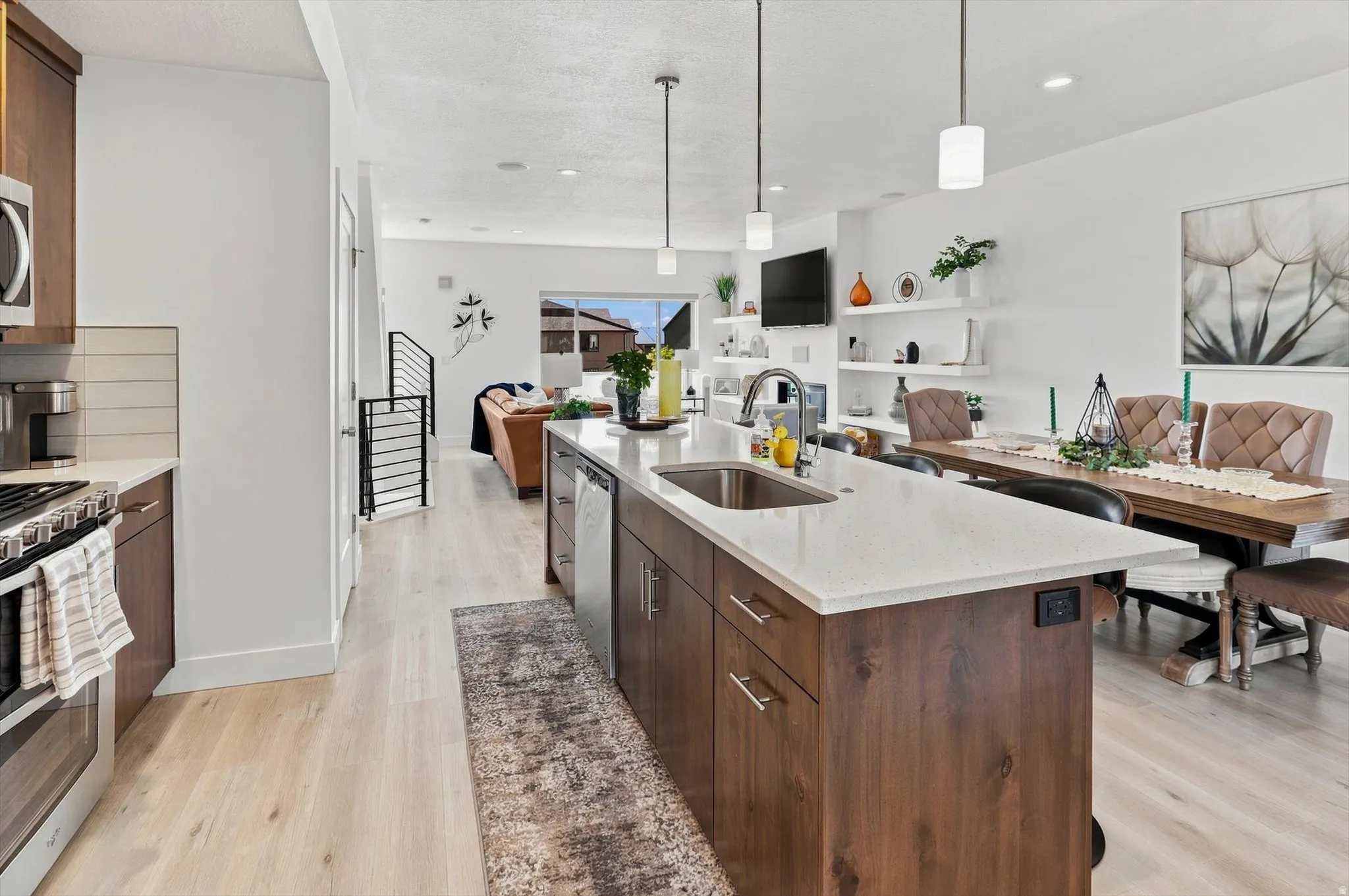 Contemporary kitchen island with a double basin sink, light-toned countertop, and rich wood-finish cabinetry