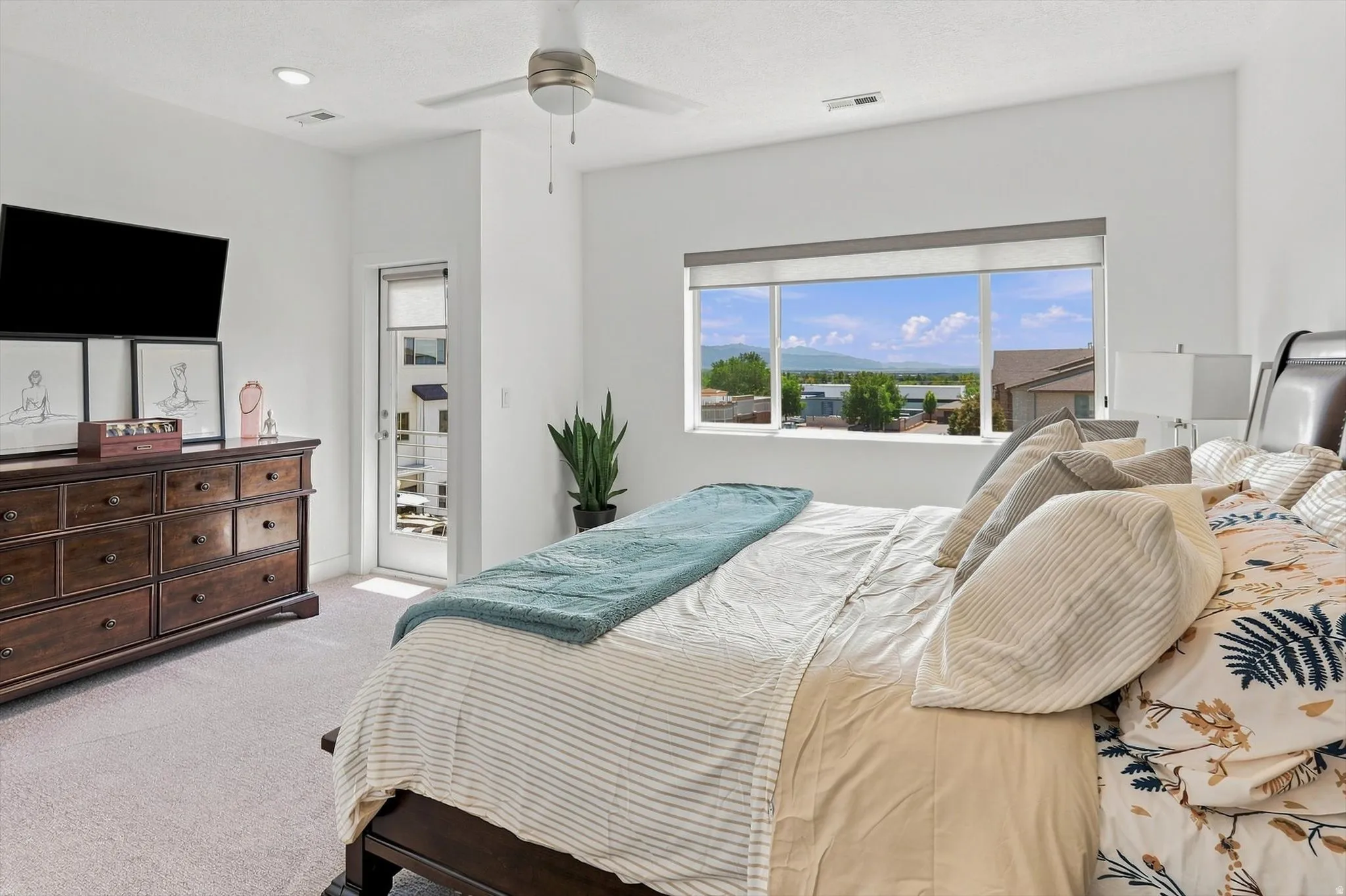 Recessed lighting, ceiling fan, carpeting, large window with roller shades, and a glass-paneled door