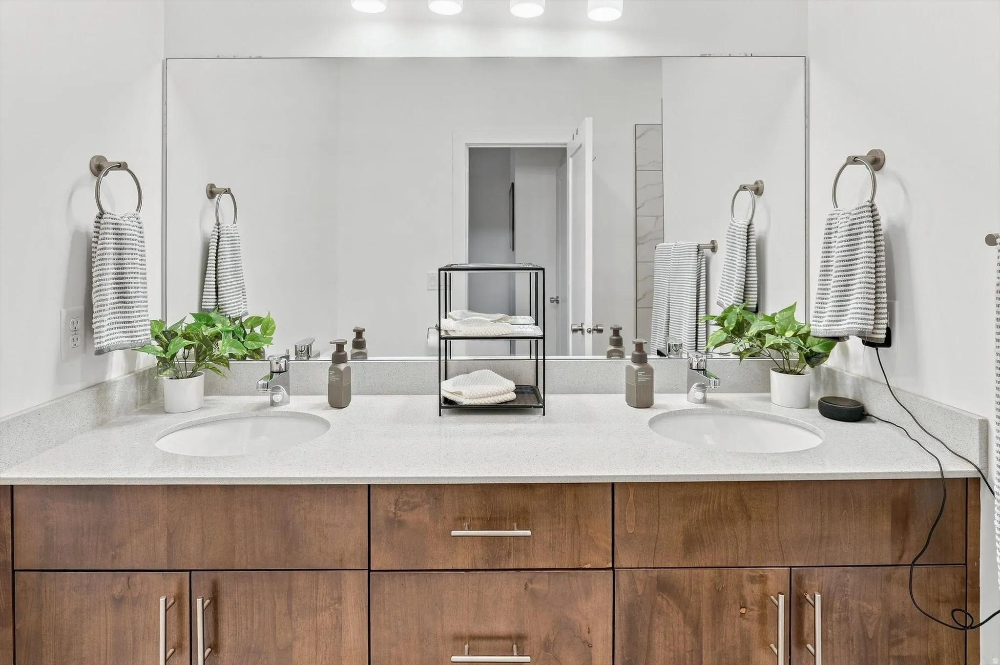 Dual undermount sinks set into a light-colored countertop, complemented by wood-finish cabinetry with brushed nickel hardware