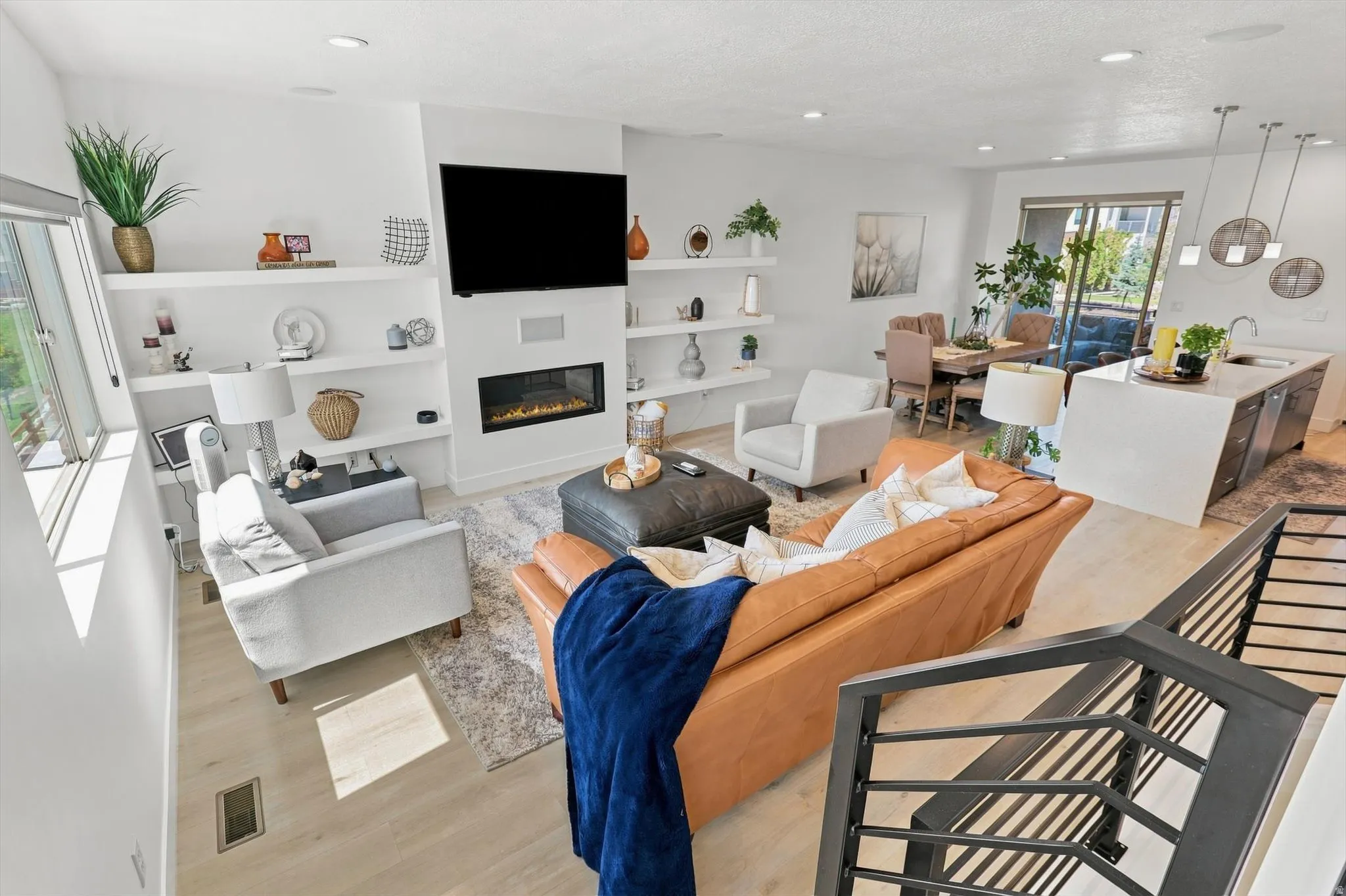Spacious living area featuring light wood-finish flooring, a contemporary fireplace, and integrated shelving