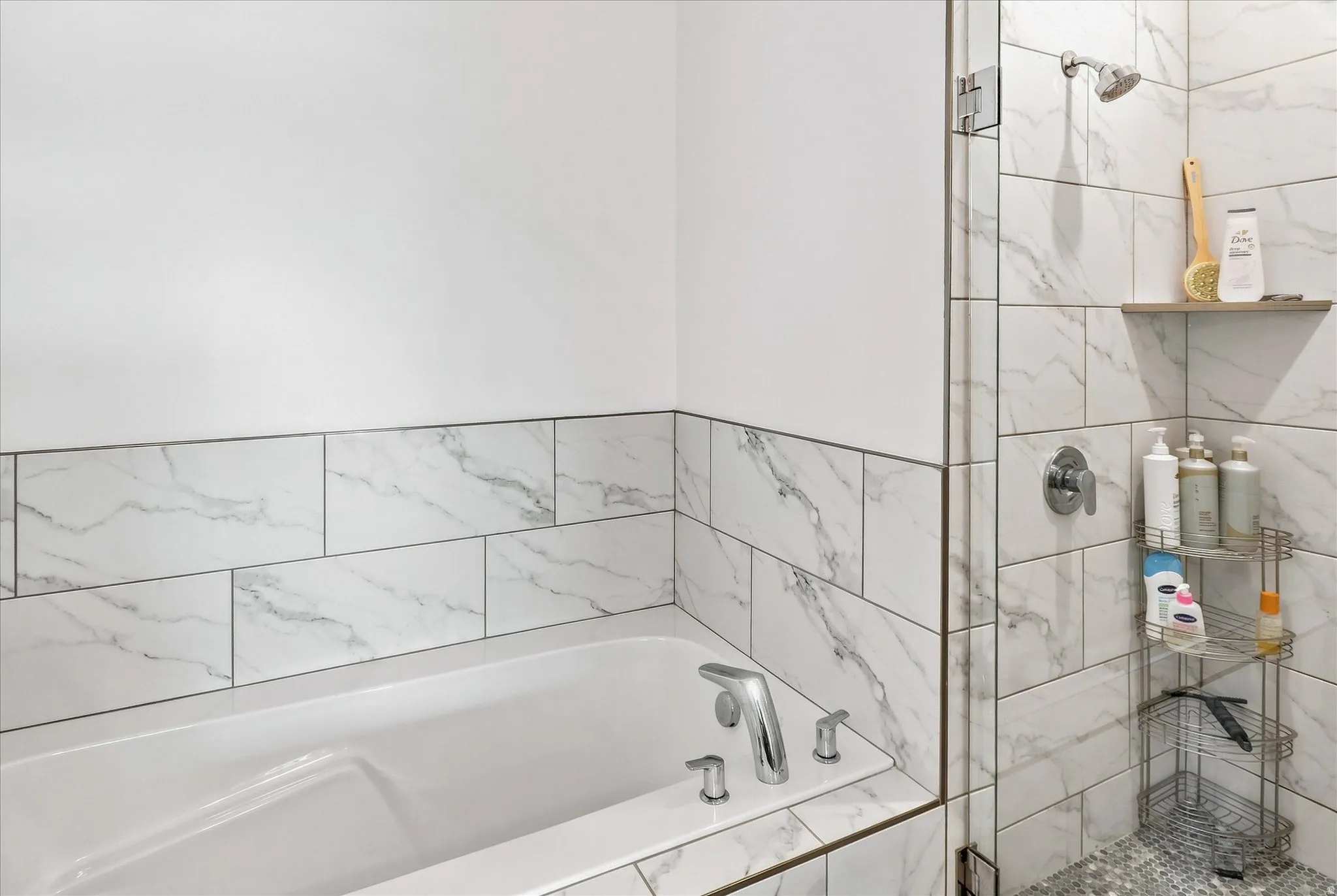 Soaking tub with chrome fixtures, surrounded by white and gray veined tile
