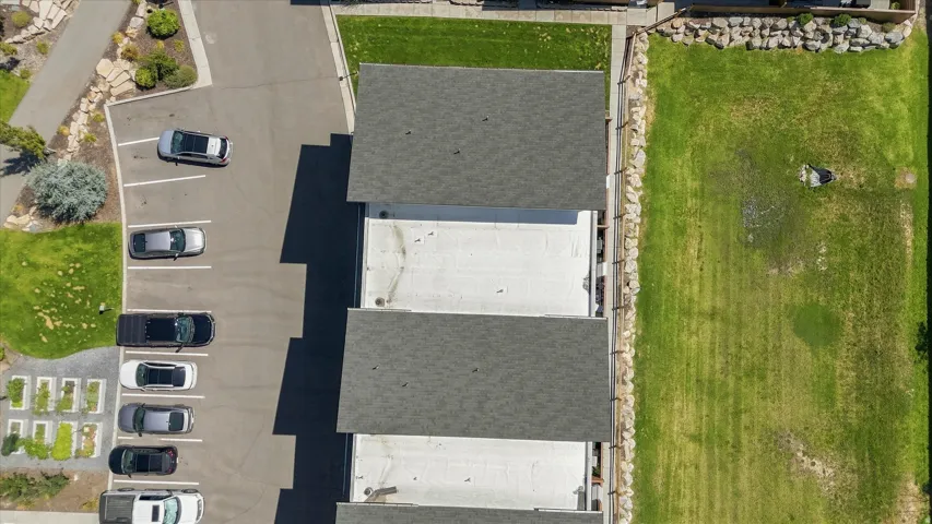 Asphalt parking lot with marked spaces, mature landscaping, and a substantial grass area