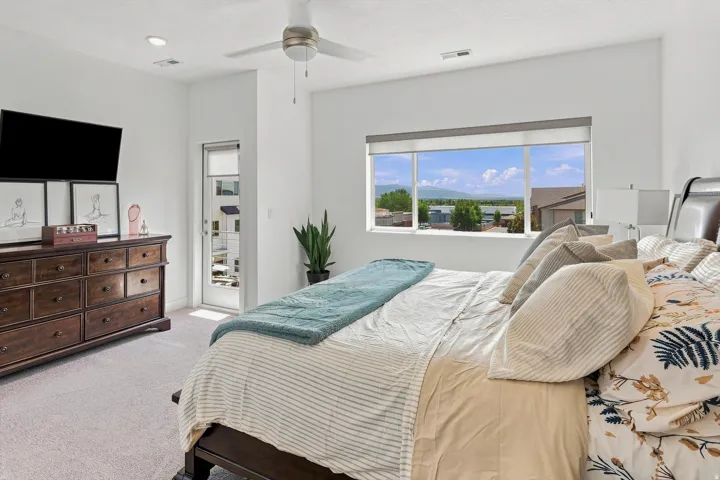 Recessed lighting, ceiling fan, carpeting, large window with roller shades, and a glass-paneled door