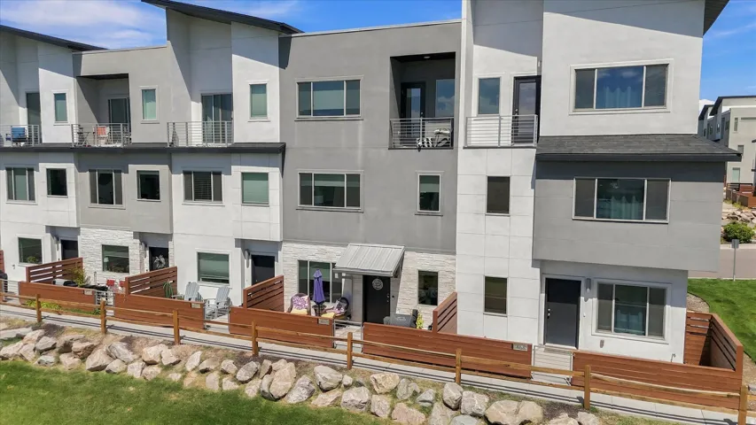 Multi-level townhome featuring a neutral-toned exterior, multiple private patios, and upper-level balconies with metal railings