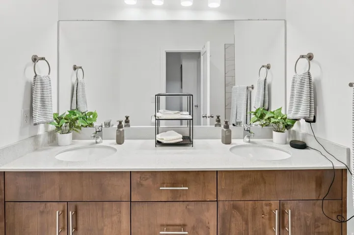 Dual undermount sinks set into a light-colored countertop, complemented by wood-finish cabinetry with brushed nickel hardware