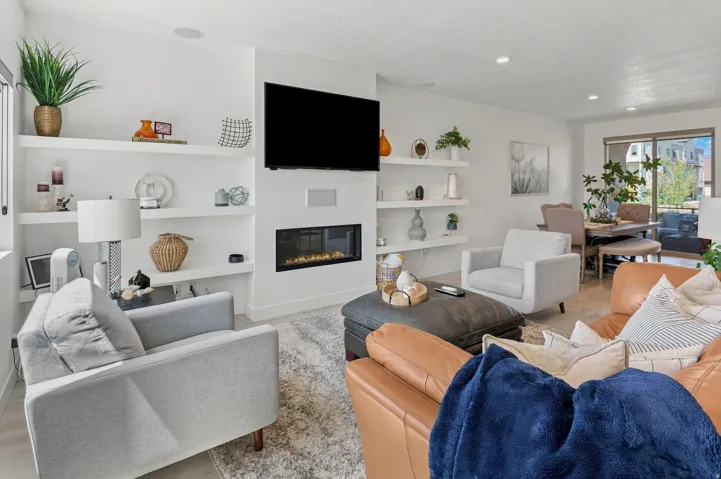 Integrated fireplace, recessed lighting, built-in shelving, wood-finish flooring, and a glass-paneled door