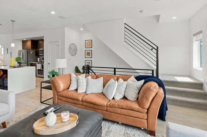 Open-concept living space featuring wood-finish flooring, recessed lighting, and a modern staircase with a black metal railing