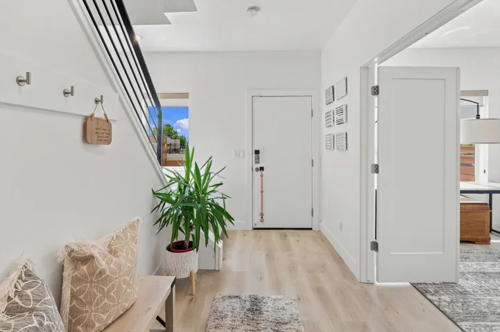 Entryway featuring light wood-finish flooring, a white paneled door, a modern black metal staircase railing, and recessed ceiling lighting