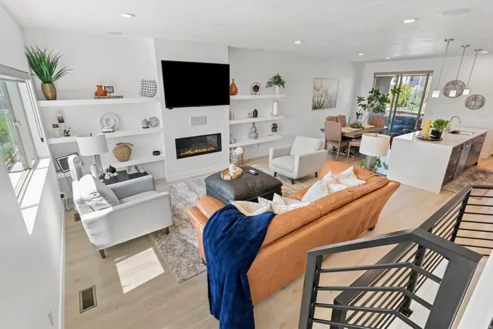 Spacious living area featuring light wood-finish flooring, a contemporary fireplace, and integrated shelving