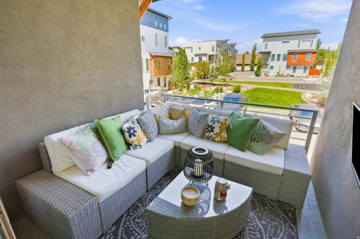 Outdoor balcony with a glass and metal railing, textured stucco wall, and a geometric pattern rug
