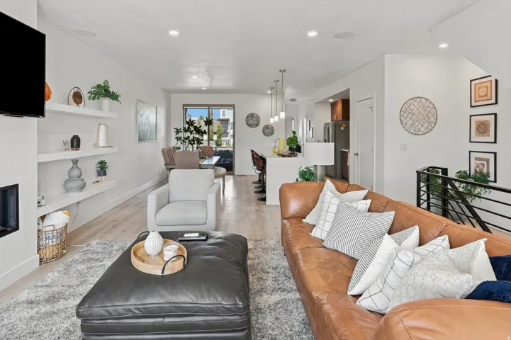 Open-concept living space featuring wood-finish flooring, recessed lighting, a modern fireplace, and built-in shelving