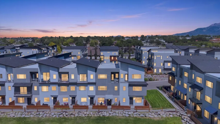 Modern architectural townhomes featuring multiple levels, balconies, and a mountain backdrop