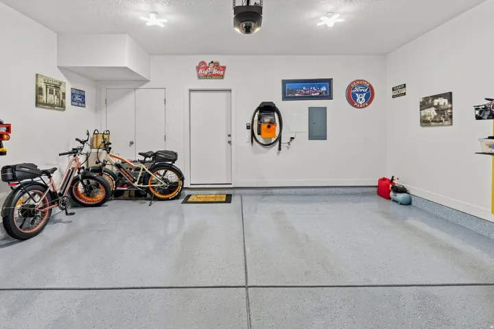 Spacious garage featuring a durable epoxy floor coating, two entry doors, and overhead lighting