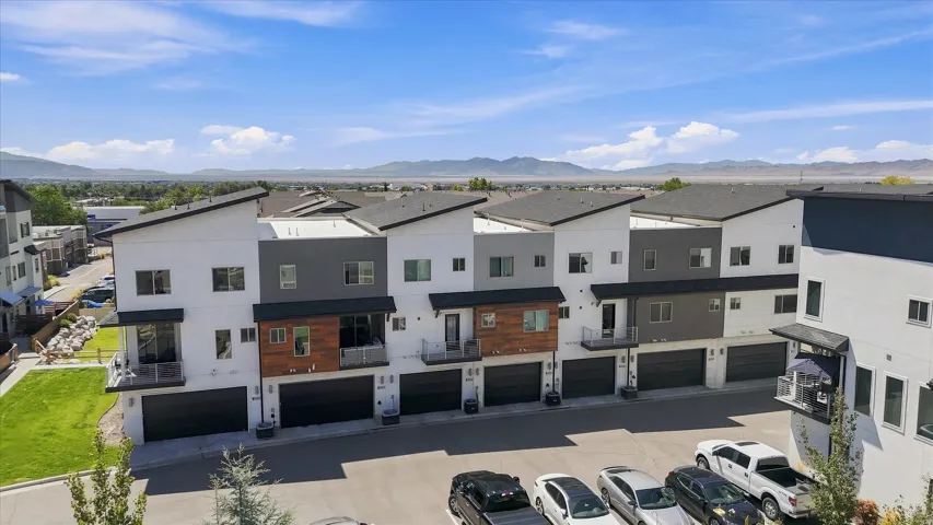 Modern townhomes featuring a multi-tone exterior, attached garages, private balconies, and a distinctive roofline