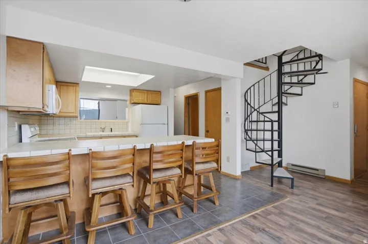 Kitchen with light wood cabinetry, tiled countertops, and a skylight