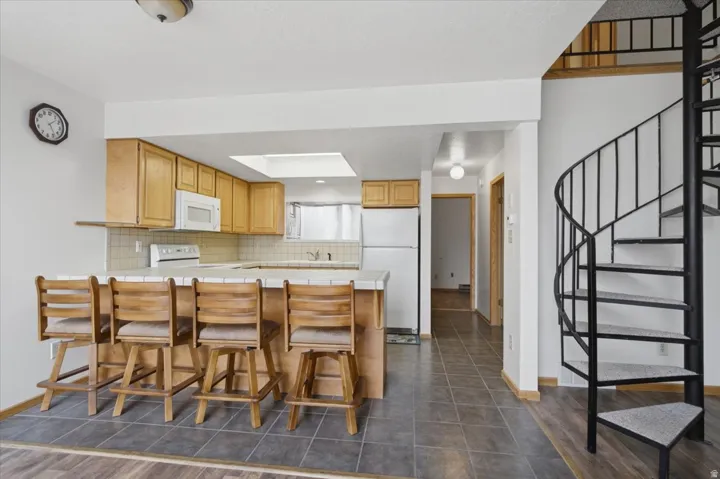 Kitchen featuring wood-finish cabinetry, white appliances, and a skylight