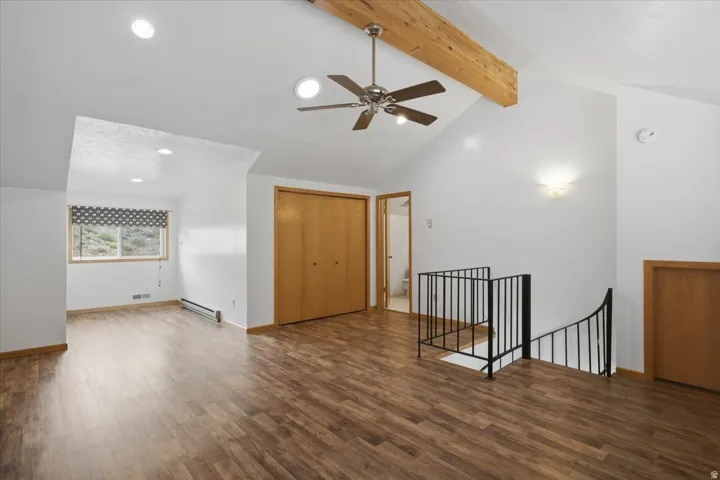 Vaulted ceiling with exposed wood beam, wood-finish flooring, recessed lighting, and a ceiling fan