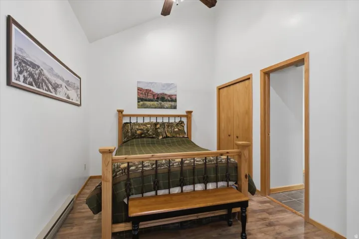 Vaulted ceiling, wood-finish flooring, natural wood closet doors, and wood door frame