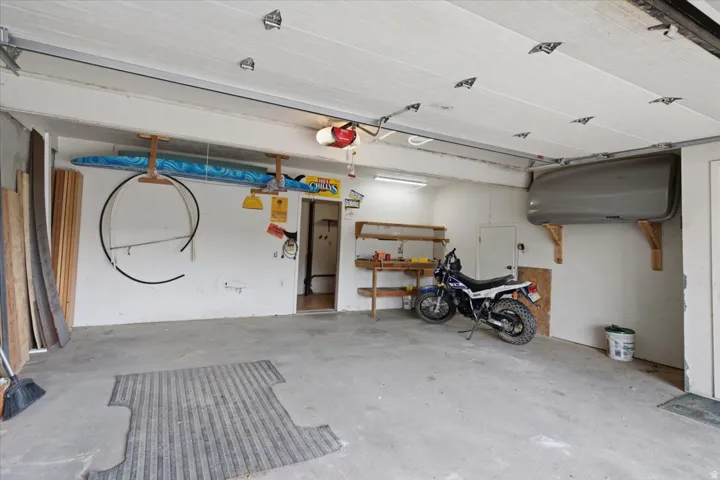 Spacious garage with concrete flooring, overhead lighting, and built-in shelving