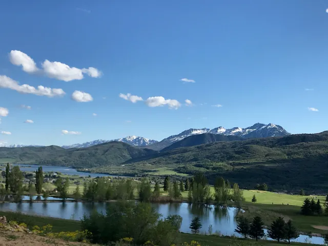 Scenic mountain backdrop, expansive lake, lush green landscape, and a pond feature